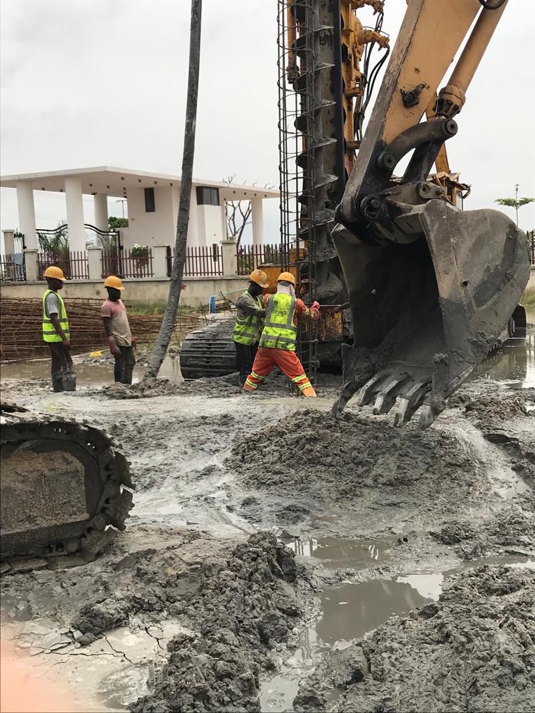 Steel reinforcement cage being installed with an excavator on waterlogged ground